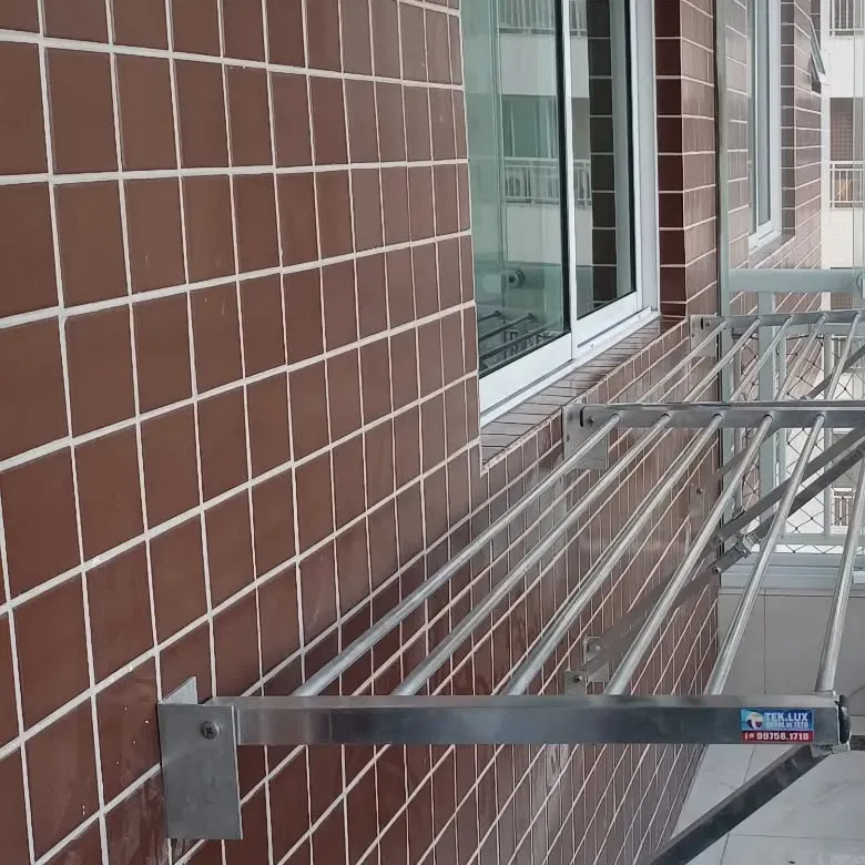 Varal de parede retrátil aberto em varanda de apartamento, com adesivo Teklux na barra